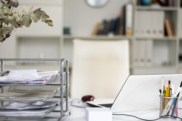 Workplace in office with white notebook, chancellery, phone and metal paper shelf on the work table