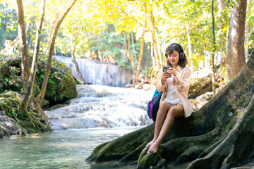 Young Asian woman travel nature on summer holiday vacation. Generation z girl enjoy and fun outdoor lifestyle using mobile phone taking selfie or vlogging with beautiful nature at forest mountain.