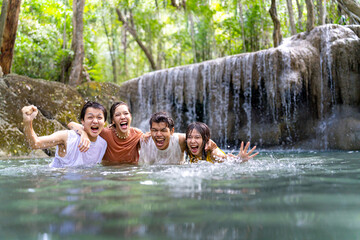 Portrait Group of Young Asian man and woman enjoy and fun outdoor lifestyle travel nature forest on summer holiday vacation. Happy generation z people friends playing water together at waterfall.