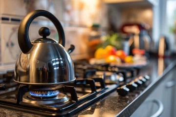 Foto op Plexiglas A silver tea kettle sits on a stove burner with a blue flame © Konstiantyn Zapylaie