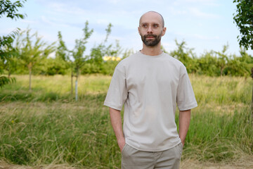 Satisfied young man 30-35 years old in light t-shirt, stylish glasses against natural background, Youth Culture and Stereotypes, younger generation, including clothing, accessories, outdoor activities