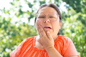 unbearable tooth pain, middle-aged caucasian woman holds on to jaw, close up female face with...