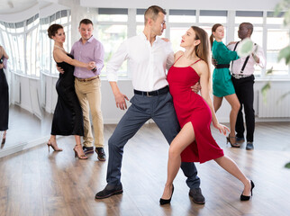 Positive young man and woman practicing waltz in pair in dancing studio