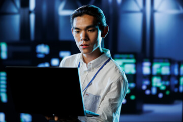 Fototapeta premium Qualified engineer between server hub rows providing processing resources for businesses worldwide. Certified expert fixing data center mainframes tasked with managing massive databases
