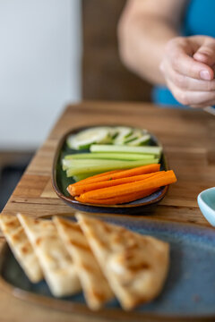 Carrots, celery, and cucumber on a plate near a bowl of hummus.