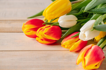 Fresh multicolored tulips on wooden background. Bouquet of spring flowers.