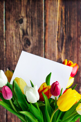 Colorful tulips bouquet and greeting card on wooden background. Holiday gift.