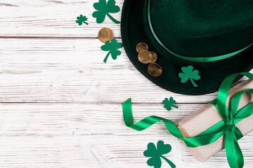 Background for St. Patrick's Day. Leprechaun hat, gold coins and clover shamrock on a white wooden...