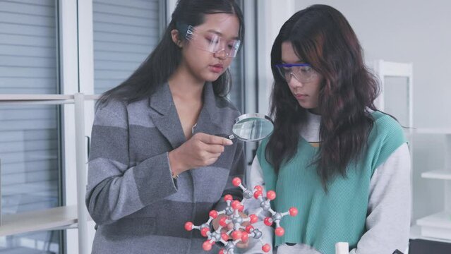 Two Asian schoolgirls are learning about molecular models in science class