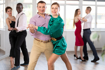 Dance studio - a group of beautifully dressed people learn to dance tango