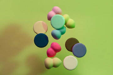 Flying different makeup sponges on green background