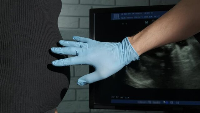 Specialist put hand on pregnant belly. A view of woman with pregnant belly refuse man hand in medical glove to put on the belly.