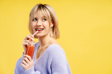 Portrait of happy young Caucasian woman holding bottle with juice or smoothie drinking, looking away