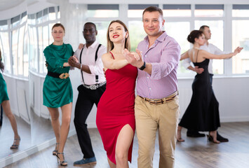 Fototapeta premium During rehearsal of reporting concert, man and woman participants of dance workshop perform figure waltz. Group training and rehearsal, preparation for competitions