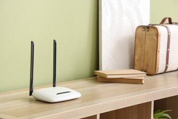 Modern wi-fi router on shelf near green wall, closeup
