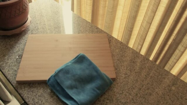 March 3, 2024 - Toronto, Ontario Canada. Examining a wooden cutting board and kitchen rag on a countertop.