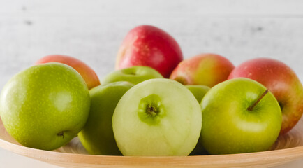 Red and green apples on a wooden plate