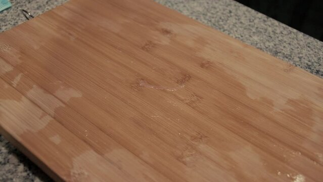 March 3, 2024 - Toronto, Ontario Canada. Close up demonstration of the removal of cut chicken from a cutting board.