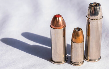 Three hollow point bullets of different calibers on a white background