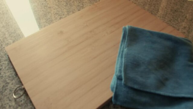March 3, 2024 - Toronto, Ontario Canada. Inspecting a wooden chopping board and rag on a counter.