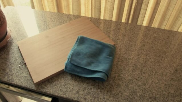 March 3, 2024 - Toronto, Ontario Canada. Examining a wooden cutting board and kitchen rag on a countertop.