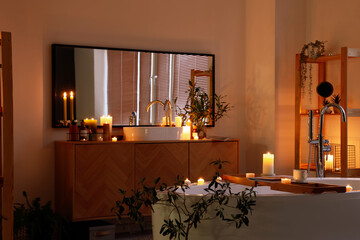 Interior of bathroom with burning candles, sink and mirror in evening