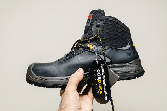 Hamburg, Germany - Feb 16, 2022: POV male hand holding new Safety shoes S3 HRO WR SRC Hydro Modytex high black - white background