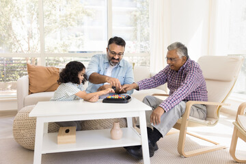 Fototapeta premium Cheerful Indian senior grandads and little granddaughter girl playing with colorful balls at home, using board game for leisure, entertainment, family playtime. Grandfathers watching child