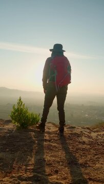 Camera follows hipster millennial young woman in green jacket up on top of mountain summit at sunrise, happy and drunk on life, youth and happiness