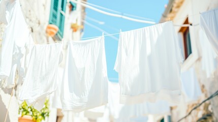 White clothes hang to dry on a line between Mediterranean buildings under a bright blue sky.