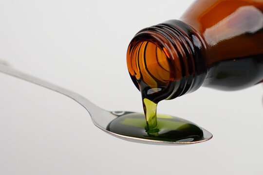 Pouring cough syrup into spoon concept background