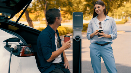 EV car recharging electricity for battery by lovey couple traveling during their road trip travel...