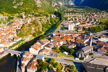 Scenic aerial view of Tarascon-sur-Ariege overlooking ancient Sainte Quitterie Church and round castle tower on tophill on bank of Ariege river - obrazy, fototapety, plakaty
