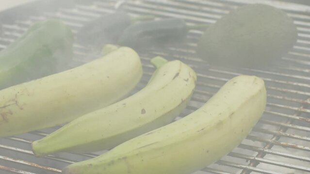 Grilled Banana on fire, latin american vegan grill with avocado and pepper, thai or Ecuadorian Street food. African traditional food on grill. 