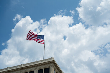 United States Flag flying on top of building with blue sky and white clouds
