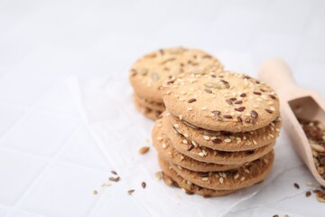 Cereal crackers with flax and sesame seeds on white tiled table, closeup. Space for text