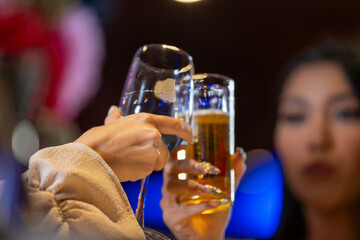 close up glasses of clinking glasses of champagne with lighting. Dinner party with drinking of champagne. hands holding clear glass with alcohol in yellow shine reflect.
