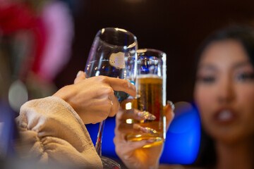 close up glasses of clinking glasses of champagne with lighting. Dinner party with drinking of champagne. hands holding clear glass with alcohol in yellow shine reflect.
