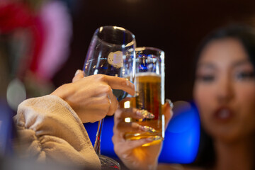 close up glasses of clinking glasses of champagne with lighting. Dinner party with drinking of champagne. hands holding clear glass with alcohol in yellow shine reflect.