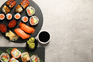 Different tasty sushi rolls on light grey table, flat lay. Space for text