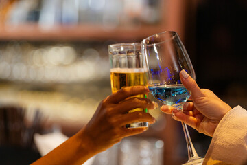 close up glasses of clinking glasses of champagne with lighting. Dinner party with drinking of champagne. hands holding clear glass with alcohol in yellow shine reflect.