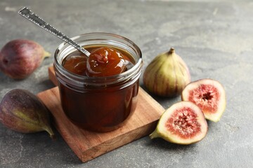 Jar of tasty sweet jam and fresh figs on grey table