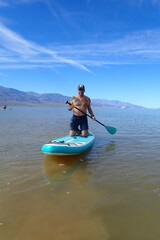 Man paddleboarding on Lake Manly, Death Valley National Park, California
