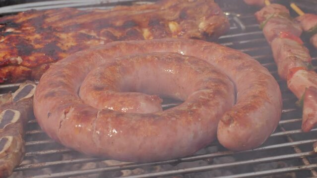 Traditional spanish barbeque, big sausage chorizo botifarra, pork and beef ribs on grill with fire, american style cooking, chef grilling meat fat food, steaks and sausages on bbq.