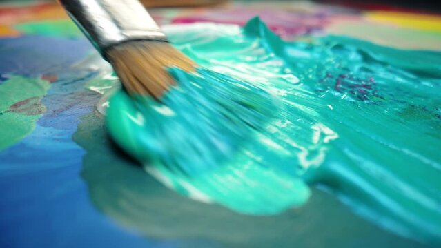 Painter mixing paints on palette. Colorful, emotional oil painting. Macro artists brush with acrylic paint. Creative workroom, abstract art. 