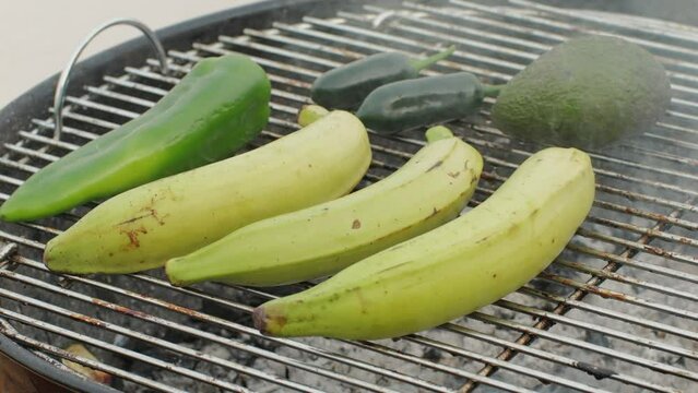 Grilled Banana on fire, latin american vegan grill with avocado and pepper, thai or Ecuadorian Street food. African traditional food on grill. 