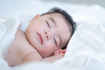 Fototapeta na wymiar 白い布に包まれて寝る赤ちゃん