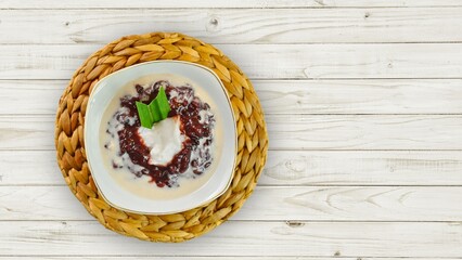 black sticky rice porridge with coconut milk sauce in a white bowl