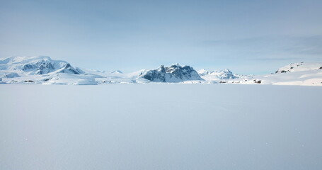 Winter Antarctica snow covered nature landscape. Frozen ocean, mountain range in background, sunny...