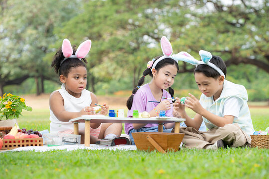 Happy family enjoying a picnic in the park, Children sitting and coloring their beautiful Easter eggs.